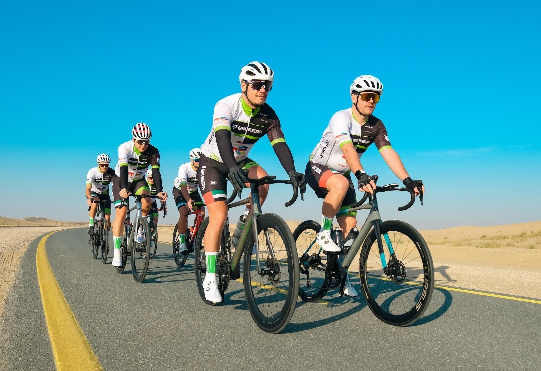 Bikeera riders in team kit on a group ride along a desert road in Dubai