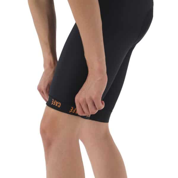 Close-up of the wide leg gripper band on the Cafe du Cycliste Cecile men’s bib short being lifted from the thigh