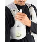 Soft flask being placed into the front chest pocket of the UltRide Evo 8 hydration vest while riding