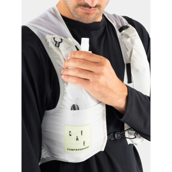 Soft flask being placed into the front chest pocket of the UltRide Evo 8 hydration vest while riding