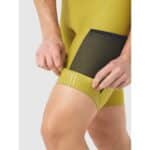 Rider loading the stretch cargo pocket on the thigh of the Cafe du Cycliste Eva V2 bib short