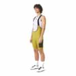 Cyclist wearing the golden olive Cafe du Cycliste Eva V2 cargo bib short, front view