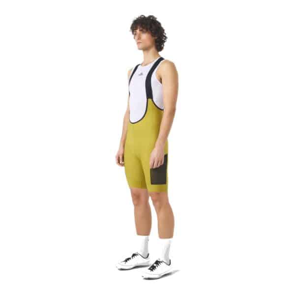 Cyclist wearing the golden olive Cafe du Cycliste Eva V2 cargo bib short, front view