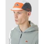 Male rider wearing the Cafe du Cycliste Gravel Summer cap, front three-quarter view showing the cycling peak
