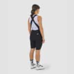 Cyclist wearing the Cafe du Cycliste Graziella bib shorts in Black, back view showing the release straps