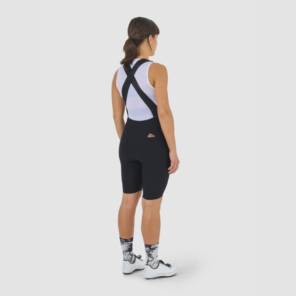 Cyclist wearing the Cafe du Cycliste Graziella bib shorts in Black, back view showing the release straps