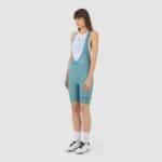 Cyclist wearing the Cafe du Cycliste Graziella bib shorts in Deep Water teal, front view