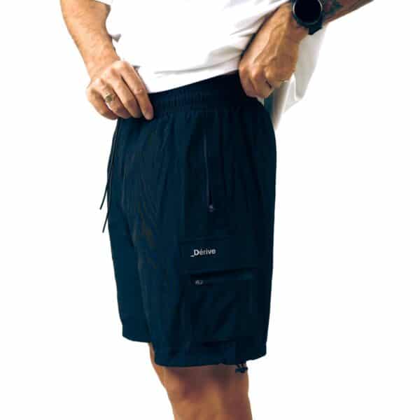 Dérive DRFT black cargo shorts, side view on model showing the thigh cargo pocket