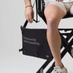 Black Dérive Purposeful Musette held by its strap, showing the side buckle and printed script