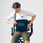 Seated rider opening the black Dérive Purposeful Musette to reach essentials