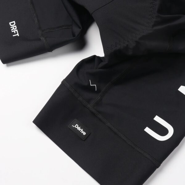 Dérive Volume bib shorts in Black, raw-edge leg with _Dérive logo tab