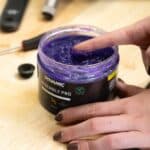 Finger scooping purple Dynamic Assembly Pro grease from the 500 ml jar
