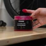 Finger with pink Dynamic Bearing Pro grease above the open 500 ml jar