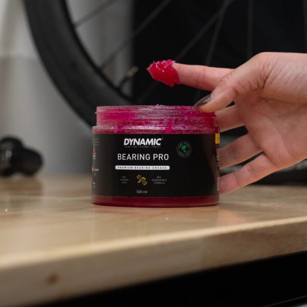 Finger with pink Dynamic Bearing Pro grease above the open 500 ml jar