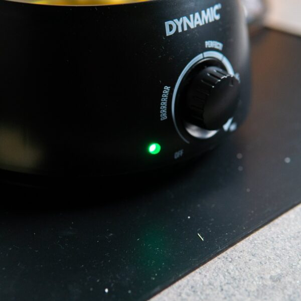 Close-up of a Waxifyer hot wax pot with melted wax on the Dynamic Mat Max