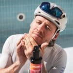Cyclist in a helmet applying Dynamic Sunsation SPF 50 sunscreen to his face