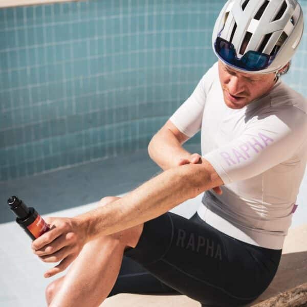 Seated cyclist rubbing Dynamic Sunsation SPF 50 into his arm before a ride