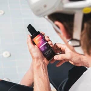 Cyclist holding a bottle of Dynamic Sunsation SPF 50 sunscreen spray before applying it