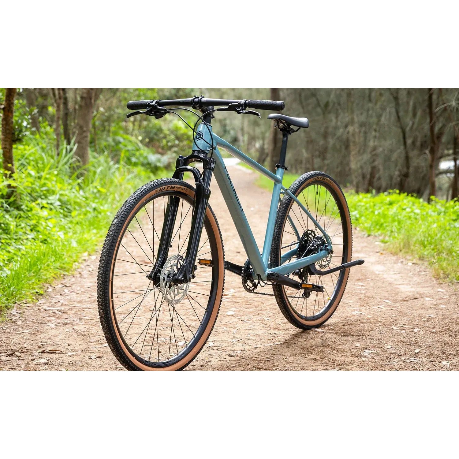 Polygon Heist 5 hybrid bike in Blue, front three-quarter view on a gravel path
