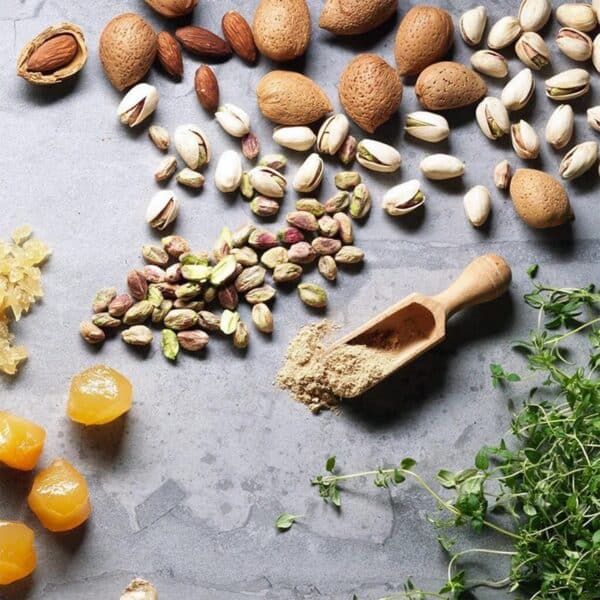 Ingredients of the Veloforte Zenzero bar laid out on a stone surface: almonds, pistachios, candied fruit and spices