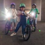 Three children on woom bikes with BEAM front lights switched on